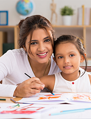 A happy mother helping daughter with schoolwork